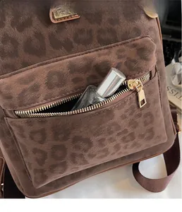 Detailed macro view of the leopard print suede backpack showing front zipper pocket storage