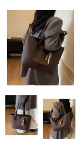 Detailed view of dark brown faux leather tote bag with lychee texture and beaded pendant