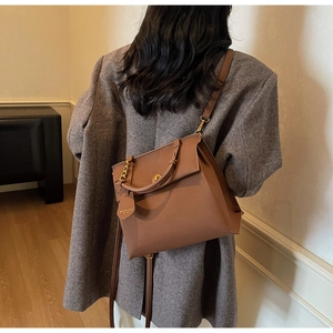 Détail d'un sac porté épaule en cuir caramel avec pendentif cœur et bandoulière chaîne