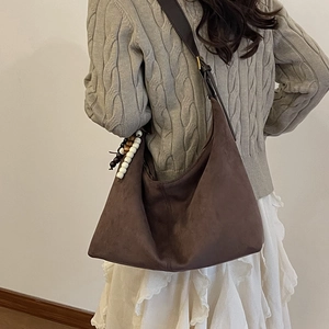 Detail view of large dark brown suede hobo bag with colorful wooden bead tassel charm