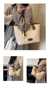 Detail of canvas tote bag with brown leather trim and elegant beaded tassel ornament