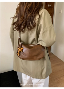 Brown moon bag detail featuring retro wooden bead tassel charms and a sleek zipper design