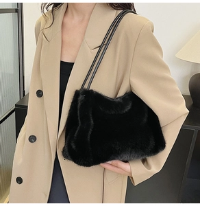 Close-up of black faux fur shoulder bag with leather straps on a camel blazer