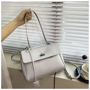 Detailed view of cream leather shoulder bag featuring silver metal twist lock and straps