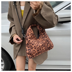 Close-up of leopard print tote bag featuring black woven strap and soft suede texture