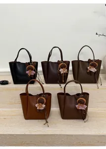 Detail view of five textured faux leather bucket bags in various colors with bear charms
