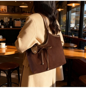 Detail of dark brown tote bag with leather bow and metallic beads on suede fabric