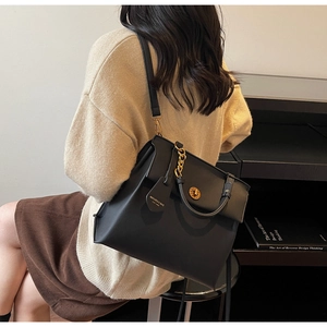 Détail du sac vintage en cuir noir avec chaîne dorée porté par un mannequin femme