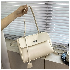 Detail of off-white bucket bag with metal twist lock and a matching square charm pendant