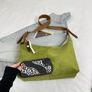 Detail of green suede hobo bag with brown leather strap and decorative vintage beads