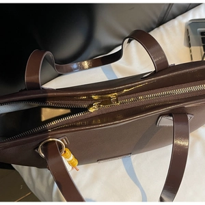 Detail of coffee tote bag with textured faux leather, gold zipper and beaded charm
