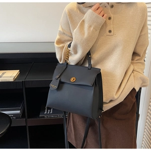 Détail du sac à main en cuir noir vintage avec boucle dorée et poignée en chaîne