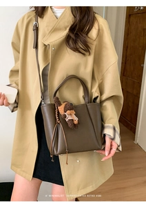 Detail of retro dark brown bucket bag with plush bear charm and woven tassel accent