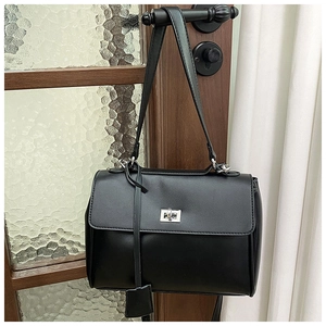 Detail of a minimalist black bucket bag with silver metal lock on a vintage door handle