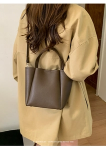 Minimalist dark brown leather bucket bag shown as a crossbody on a stylish model