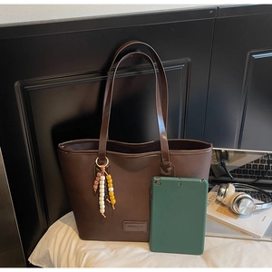 Deep brown tote bag detail showing large capacity with a tablet for size reference