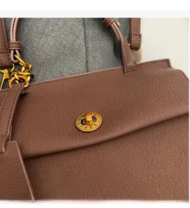 Gros plan d'un sac en cuir marron avec fermoir rotatif vintage doré style horloge