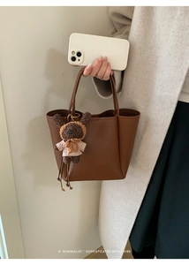 Detail of dark brown lychee pattern bucket bag with a cute plush bear charm accessory