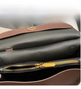 Gros plan sur la fermeture éclair en métal doré et la texture du cuir d'un sac vintage