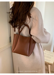 Brown leather bucket bag shown from a side view on a model for everyday commute style