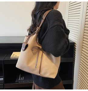 Detail of apricot tote bag with leather bow, wide strap and metallic ball charm