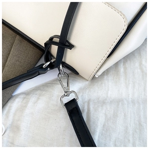 Close-up of cream leather bucket bag with black edge painting and silver metal hardware