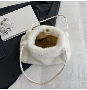 Detail of white faux fur shoulder bag featuring a gold magnetic closure and cream leather strap