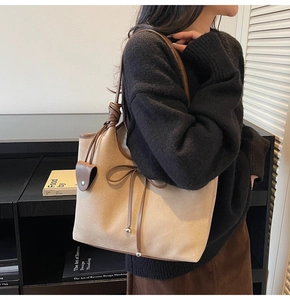 Detail of khaki tote bag featuring knotted shoulder strap and elegant bow decoration