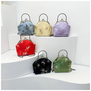 Détail de sacs coquillage en soie avec jacquard de bambou et poignées en métal bambou