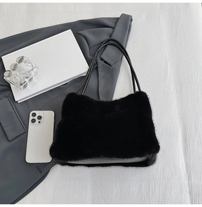 Close-up of black faux fur shoulder bag with leather straps on a grey blazer background