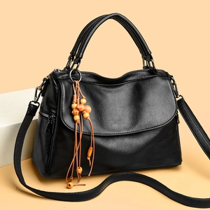 Close-up of litchi texture black Boston bag with ethnic wooden bead tassel detail