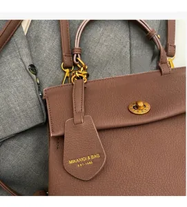Détail de sac à main en cuir marron foncé avec fermoir rotatif en métal doré vintage
