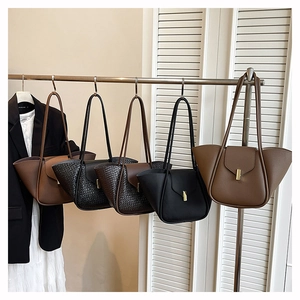 Multiple textured tote bags with metallic buckles hanging in a row showing color variety
