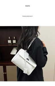 Detail view of white matte leather crossbody bag with silver twist lock and slim strap