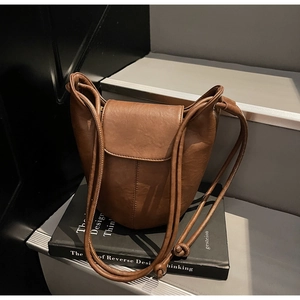 Detail of vintage brown leather bucket bag with flap closure and adjustable knotted strap