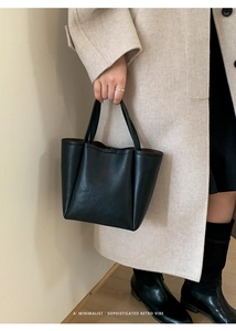 Detailed view of black pebbled leather bucket bag with sturdy handles for commute
