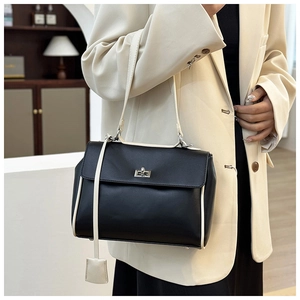 Detail of minimalist black and beige leather bag featuring silver metal twist lock buckle