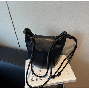 Detailed view of black soft leather bucket bag with slim shoulder strap on art books