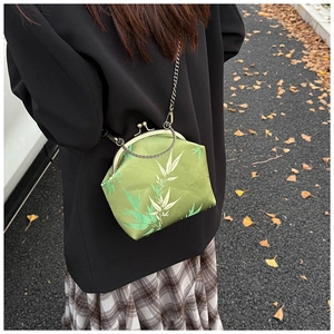 Détail du sac fermoir en satin vert avec motif bambou et chaîne métallique