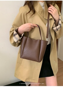 Deep brown pebble leather bucket bag with retro minimalist vibe shown on model