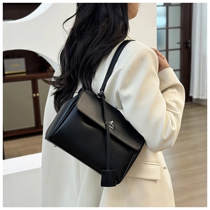 Detail of a minimalist black leather crossbody bag featuring a sleek metal buckle closure