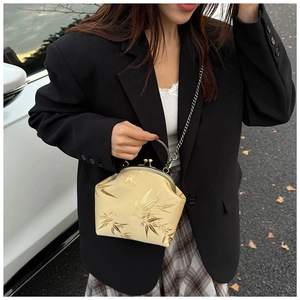 Détail du jacquard de feuilles de bambou doré et de la poignée rétro en métal du sac