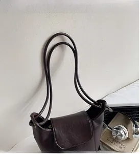 Macro detail of dark coffee bucket bag featuring textured leather and slim shoulder straps