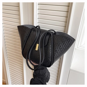 Detailed view of black woven leather tote bag with elegant golden metallic clasp detail