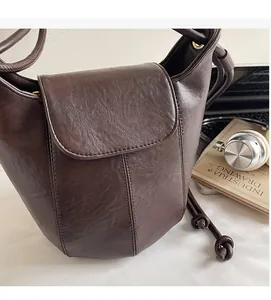 Detail of dark brown bucket bag with lychee texture and drawstring on office desk