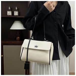 Detail of minimalist cream bucket bag with black trim and silver buckle in retro setting