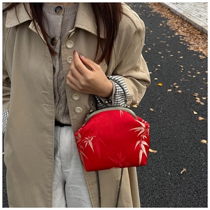Détail d'un sac rétro rouge avec broderie de feuilles de bambou et chaîne métal