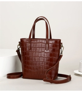Detail of brown crocodile pattern tote bag with dual handles and adjustable strap