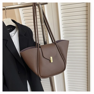 Detailed view of the dark brown lychee textured leather tote bag with gold metal hardware