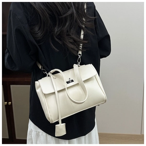 Detail view of cream bucket bag with silver twist lock and crossbody strap on model